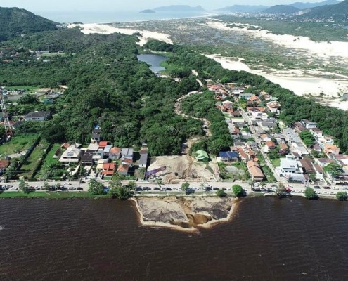 Fotografia aérea de drone mostra a Lagoa da Conceição com águas de tonalidade marrom-avermelhada e com grande banco de areia em frente à Avenida das Rendeiras. Resultado de rompimento de lagoa de tratamento de efluentes.